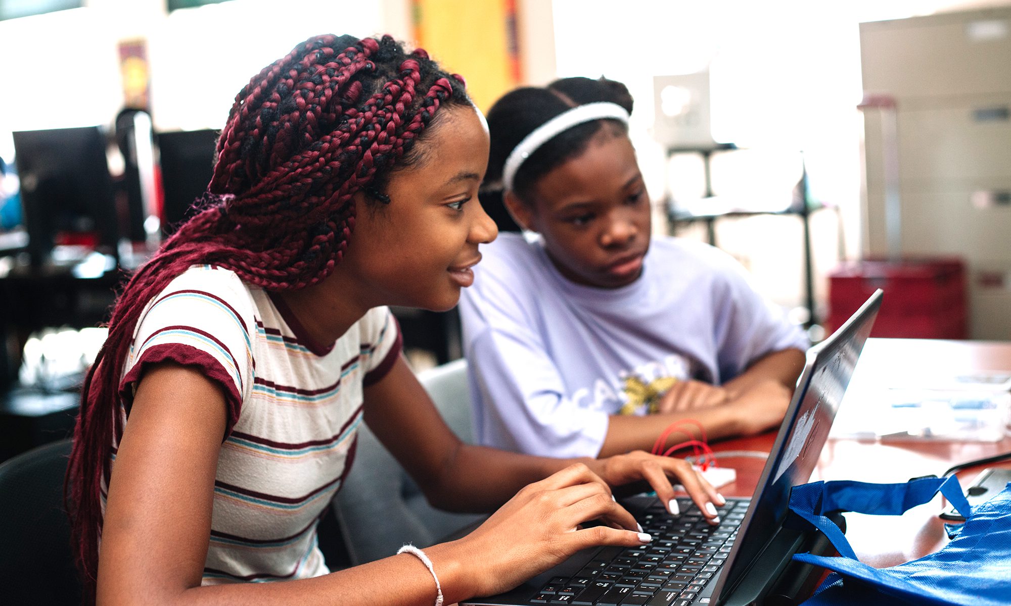 Two AA female youth look at a computer in class