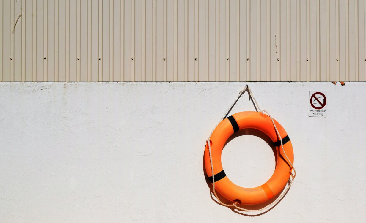 An orange life saver is hanging on a white wall